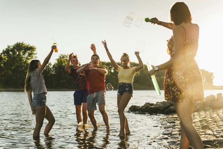 Group of happy friends in a river at sunset